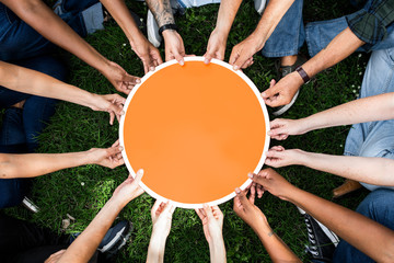 Group of people holding a round orange board