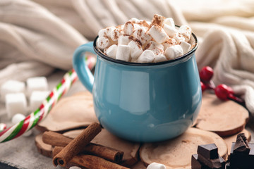 Mug of hot chocolate with marshmallow and a Lollipop on a knitted blanket background. Cozy warm winter composition