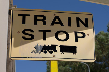 Road sign with the inscription in English "train stop" and the symbol of the locomotive black
