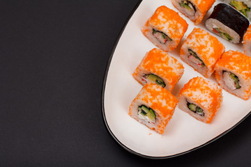 Uramaki California. Sushi rolls on a plate with black background.