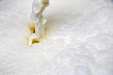 Milk Flowing From The Tap Making White Foam And Bubbles Close Up