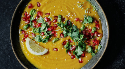 Fresh pumpkin soup topped with parsley and pomegranate seeds