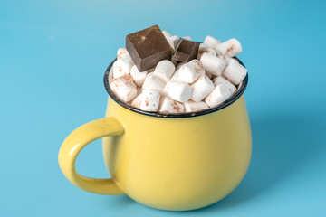 Mug of hot chocolate with marshmallows on top on a blue background. Cozy winter card