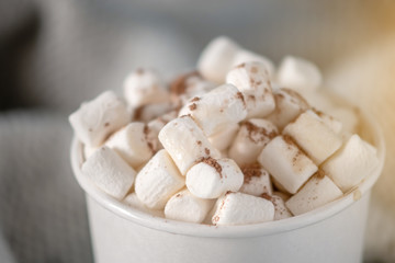 White paper Cup of hot chocolate with marshmallow on top on blue background. Cozy warm card