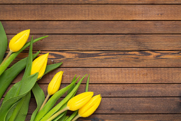 Beautiful yellow tulips on wooden background. Top view, copy space. Holidays concept. Add text