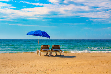 Fototapeta na wymiar Two sunbeds under an umbrella on the beach