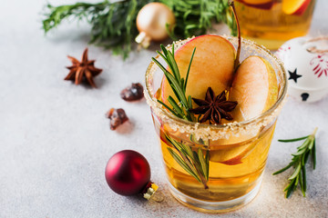 Traditional Christmas apple punch with cinnamon, anise and sprigs of rosemary on light background. Selective fоcus. Top view.