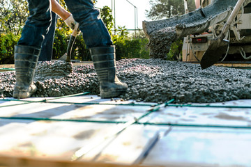 Mixer track pouring wet cement to the civil building foundation. Construction workers in the...