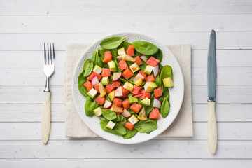 Poke Hawaiian salad with salmon, avocado spinach and vegetables in a plate on a white table.