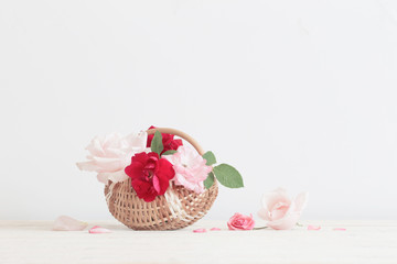 beautiful roses in basket on wooden table