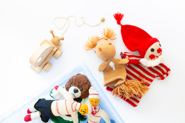 Top view of cute and funny vintage children toys in a blue plastic box on white background. Assortment consists of a clown, a squirrel, a teddy bear, dolls and a wooden snail.