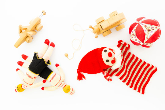 Top view of funny vintage children toys on white background. Assortment consists of a clown, dolls, a wooden grasshopper, a wooden snail and a ball.