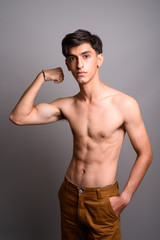 Fototapeta premium Young handsome Persian teenage boy shirtless against gray backgr