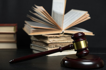 Judge gavel beside pile of books on wooden background