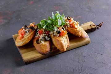 Crispy toasts with tomato, olives, arugula and cheese