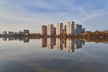 Panoramic View to the west of Krasnodar from the Kuban River in the winter at golden hours. New high-rise buildings and their reflection in the water surface. In the background is a clear blue sky.