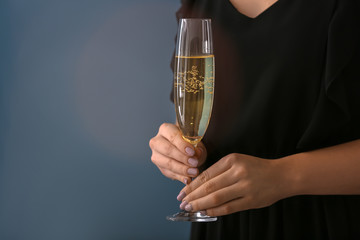 Woman with glass of champagne on color background