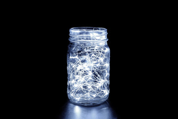 White fairy light in a mason jar, in the dark, low-key photography