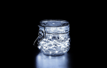 White fairy light in a glass jar, in the dark, low-key photography