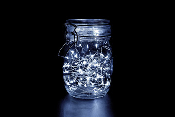 White fairy light in a glass jar, in the dark, low-key photography