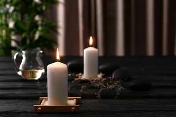 Beautiful composition with burning candles and spa stones on dark wooden table