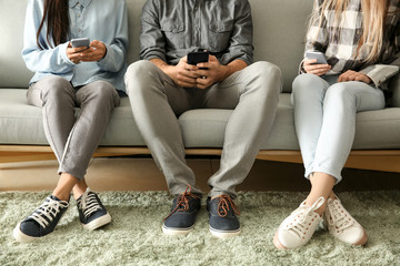 Young people using mobile phones on sofa. Concept of addiction
