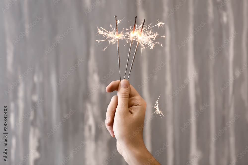 Wall mural woman holding christmas sparklers on grey background