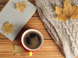 Naklejka na ściany i meble Mug of hot coffee with a warm knitted sweater and a book