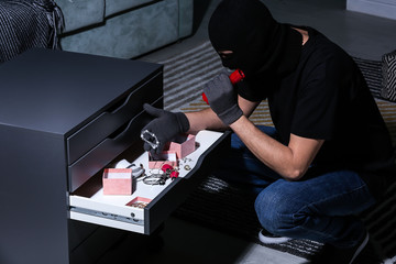 Male thief looking for valuables in flat