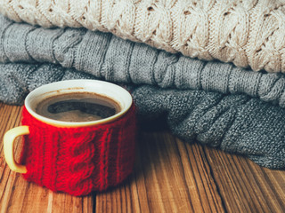 Obraz na płótnie Canvas Coffee mug on the background of warm knitted sweaters