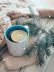 Mug with hot tea on the table with a warm scarf and a book.