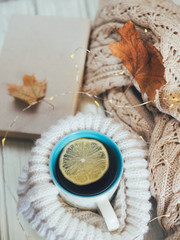 A mug of hot tea next to a warm sweater