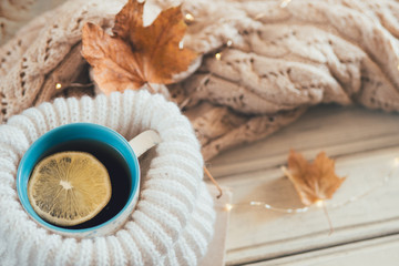 A mug of hot tea next to a warm sweater