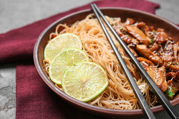 Plate with tasty chinese noodles and meat on table, closeup