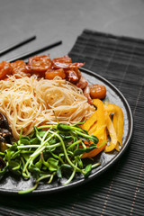 Plate with tasty chinese noodles, shrimps and vegetables on table, closeup