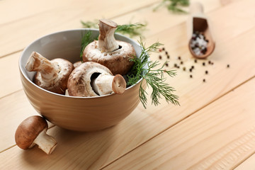 Fototapeta na wymiar Bowl with fresh mushrooms on wooden table