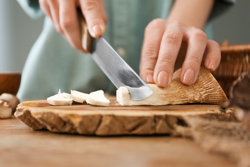 Woman cutting raw mushrooms on wooden board