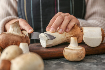 Obraz na płótnie Canvas Woman cutting raw mushrooms on wooden board