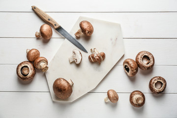 Fresh mushrooms with board on white wooden table
