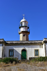 Fototapeta na wymiar Old abandoned lighthouse with wind vane. Sunny day, blue sky. Galicia, Spain.