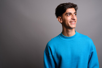 Young happy Persian teenage boy smiling and thinking