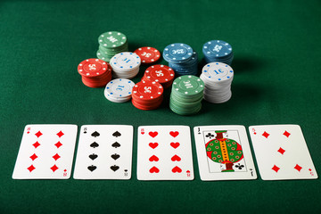 Chips with cards for poker game on green table