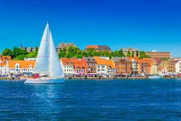 Wandaufkleber Beautiful panorama of a European port city. A yacht is sailing against the skyline of the city of Flensburg, Germany © Travellaggio