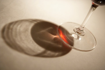 GLASS OF RED WINE CASTING SHADOW ONTO WHITE TABLE CLOTH
