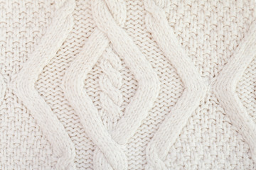 Knitted white fabric texture with a relief pattern. Warm winter clothes or blanket. Handmade texture