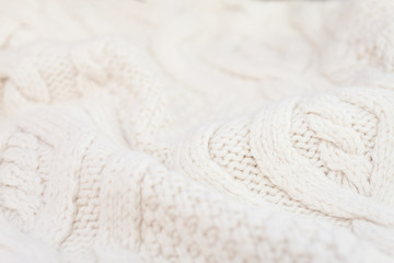 Knitted white fabric texture with a relief pattern. Warm winter clothes or blanket. Handmade texture