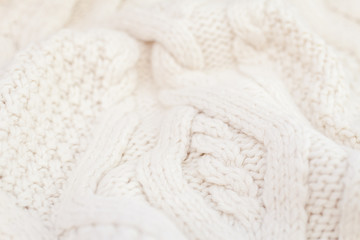 Knitted white fabric texture with a relief pattern. Warm winter clothes or blanket. Handmade texture