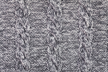 Knitted grey fabric texture with a relief pattern . Warm winter clothes or blanket. Handmade texture