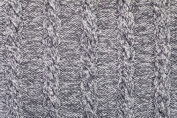 Knitted grey fabric texture with a relief pattern . Warm winter clothes or blanket. Handmade texture