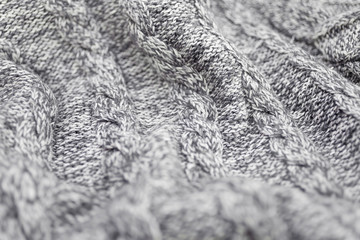 Knitted grey fabric texture with a relief pattern . Warm winter clothes or blanket. Handmade texture
